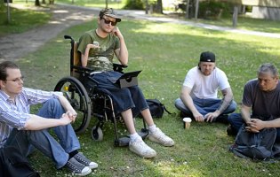 Screenshot Video "Studieren mit Behinderung" Auf dem Bild sind Fidi und andere Studenten zu sehen, die auf der Wiese ihren Unikurs abhalten.