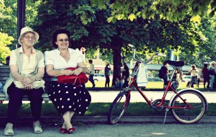 Zwei ältere Frauen auf Parkbank, neben der ein Fahrrad steht