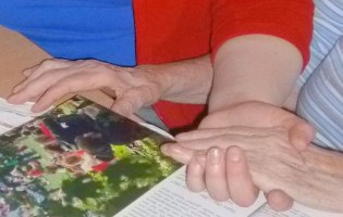 Zwei paar Hände: eine alte Person legt ihre Hand in die der jungen