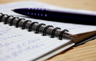 Ein beschriebener Notizblock mit Stift