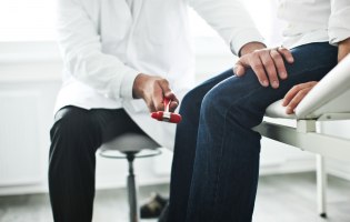 Arzt testet Kniereflex bei Patienten