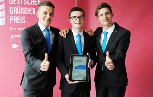 Drei Schüler im Anzug lächeln in die Kamera