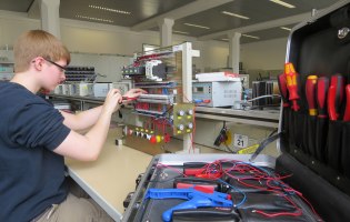 Isabel arbeitet am Werktisch, daneben ein aufgeschlagener Werkzeugkoffer