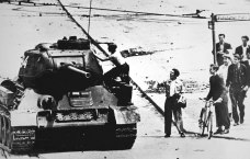 Mann klettert auf Panzer, daneben andere Männer, die ihm zusehen